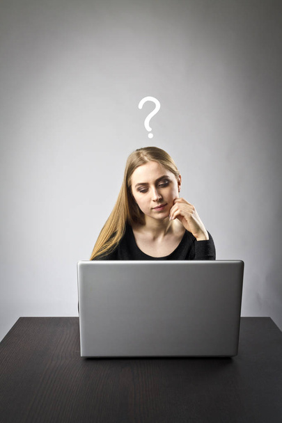 Jonge vrouw met behulp van een laptop te surfen op het net. Vraag, onwetendheid en moeite concept. - Foto, afbeelding