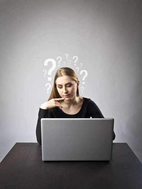 Mujer joven usando un ordenador portátil para navegar por la red. Preguntas, ignorancia y concepto de problemas
. - Foto, imagen