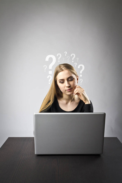 Nuori nainen käyttää kannettavaa tietokonetta selatakseen verkkoa. Kysymyksiä, tietämättömyys ja ongelmia käsite
. - Valokuva, kuva