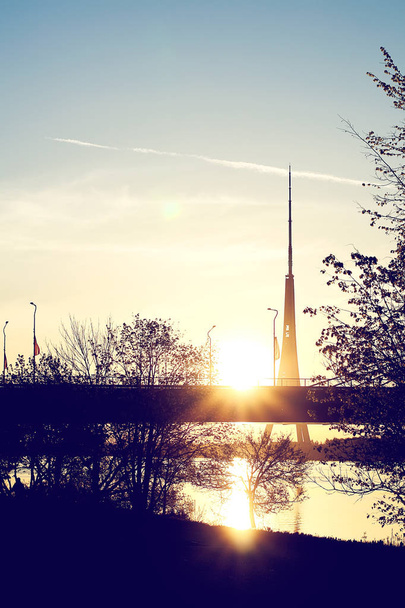 Wieczorny krajobraz z sylwetką mostu na tle zachodzącego słońca. Ryga, Łotwa, Europa Wschodnia. - Zdjęcie, obraz