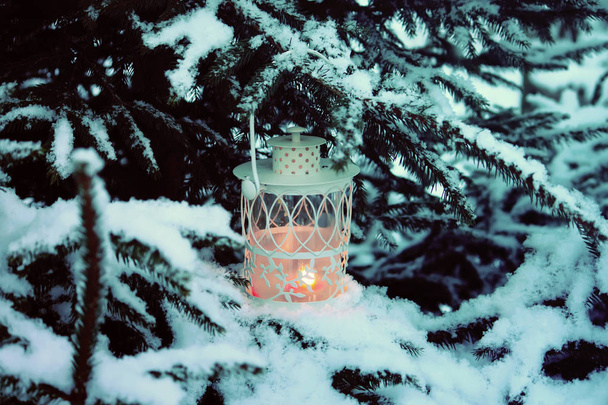 Christmas lantern with burning candle on winter nature background. - Foto, afbeelding