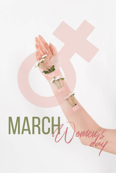 cropped view of woman with wildflowers on hand on white background with womens day illustration  - Zdjęcie, obraz