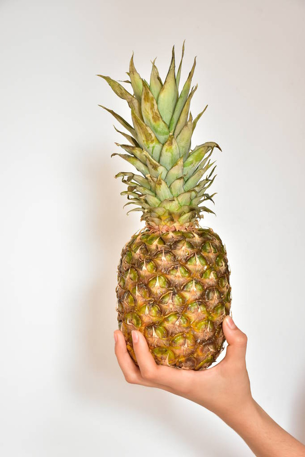 Hand und Ananas auf weißem Hintergrund - Foto, Bild
