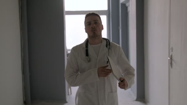 A doctor with a stethoscope goes through the corridor of the hospital - Materiał filmowy, wideo