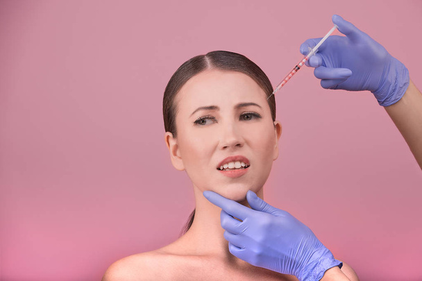 Beautiful woman face and beautician hands with syringe. Doctor makes cosmetic injection in the upper lip. Clean Beauty concept - Photo, Image