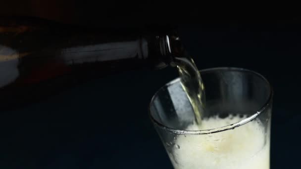 Pouring craft beer from the bottle into drinking glass on dark background close up. Sllow motion full hd video - Materiaali, video