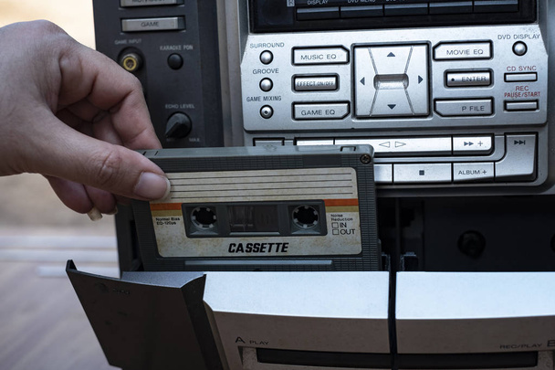 Vrouwen hand cassette ingebruikneming oude ouderwetse tape audiospeler op top bureau houten achtergrond - Foto, afbeelding