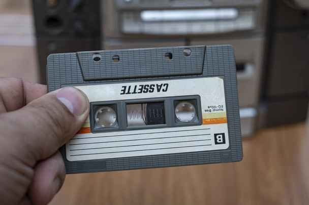 トップ デスク木製背景に古い昔ながらオーディオ テープ プレーヤーにカセットを入れて男の手 - 写真・画像
