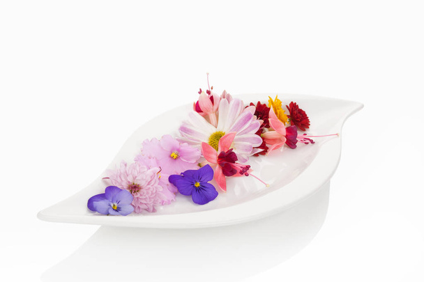 Delicious salad made from mix edible flower on white plate over white background. Culinary fresh salad from above. - Valokuva, kuva