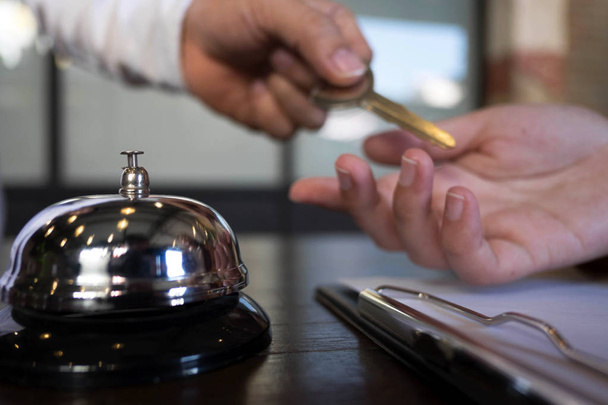 Κοντινό πλάνο της πελατών χέρι λαμβάνει το κλειδί του δωματίου στο γκισέ check-in του ξενοδοχείου. Ξενοδοχείο έννοια. - Φωτογραφία, εικόνα