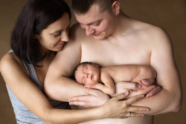 Hermosa madre y padre sonriendo sosteniendo a su bebé recién nacido
 - Foto, Imagen