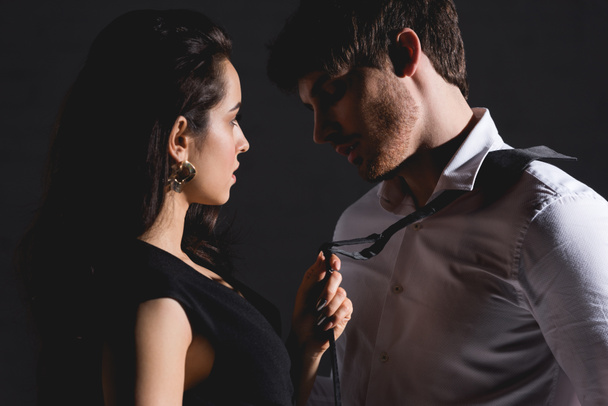 hombre en camisa blanca y mujer en vestido de pie y mirando el uno al otro aislado en negro
 - Foto, imagen
