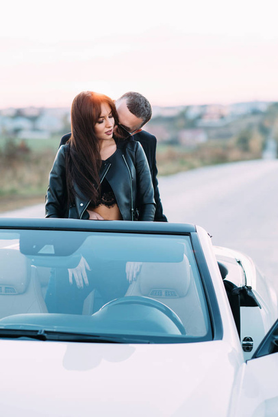 Couple sympathique mari et femme passent du temps à l'extérieur de la ville et s'asseoir dans une voiture cabriolet sur le siège arrière
. - Photo, image