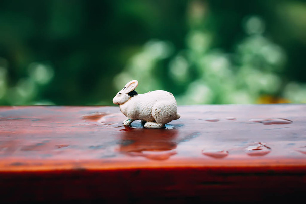 Pequeño conejo de juguete blanco en una superficie de madera al aire libre
. - Foto, imagen