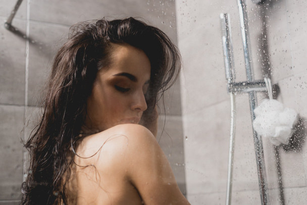 brunette and naked woman taking shower in cabin  - Фото, зображення