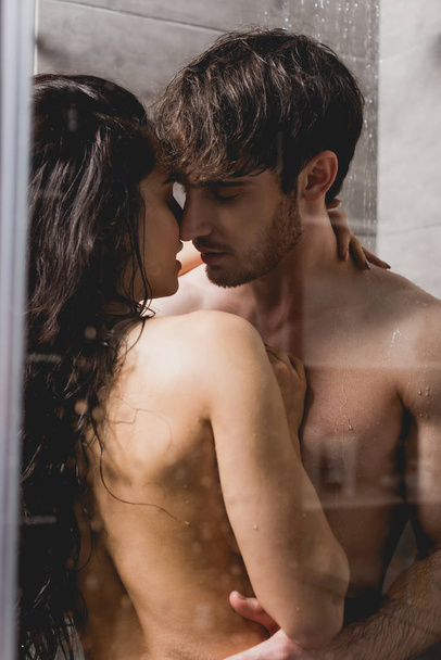 handsome man and beautiful woman hugging in shower cabin  - Photo, Image