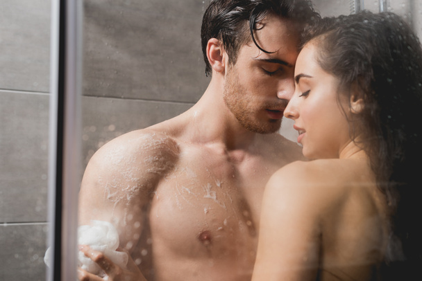 man and woman hugging and taking shower with loofah in cabin  - Foto, afbeelding
