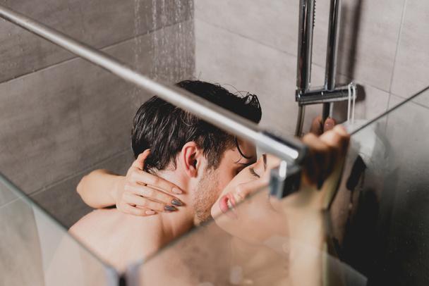 Nackter Mann und schöne Frau umarmen und küssen sich in Duschkabine  - Foto, Bild