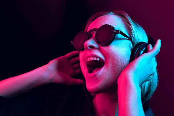 Fashion pretty woman with headphones listening to music over neon background - Fotoğraf, Görsel