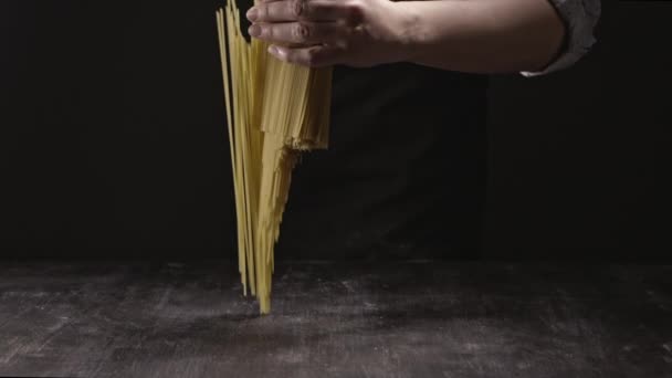 bunch of spaghetti in hands of woman on dark background,  concept of Italian food - Video