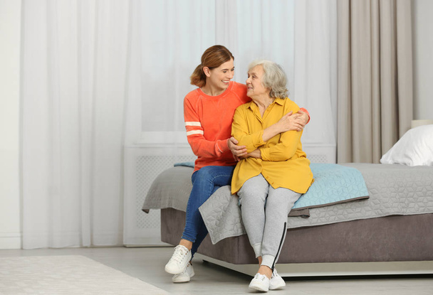 Elderly woman with female caregiver in bedroom. Space for text - Fotografie, Obrázek