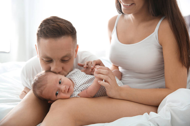Happy couple with their newborn baby on bed - Fotó, kép
