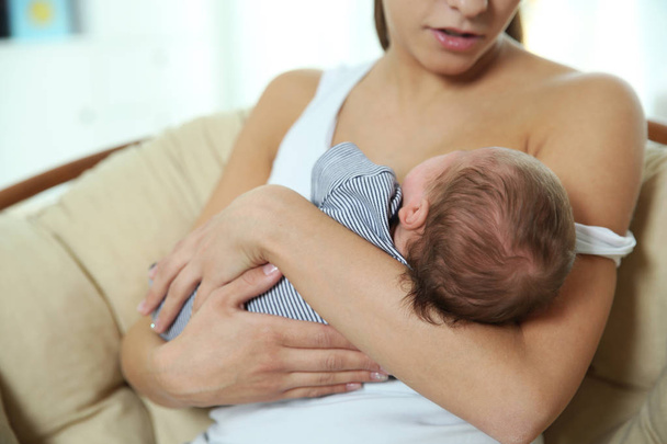 Mujer joven amamantando a su bebé en casa, primer plano - Foto, imagen