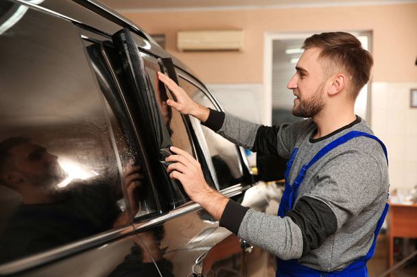 Worker tinting car window with foil in shop - Foto, imagen