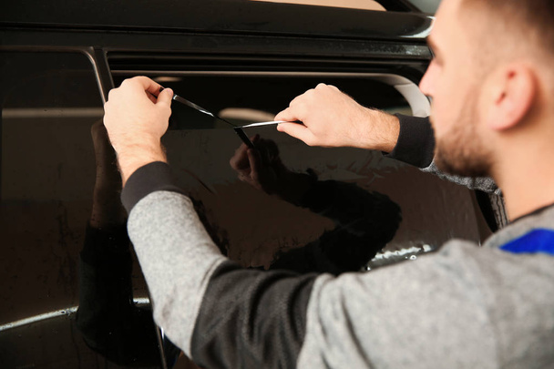 Skilled worker tinting car window in shop - Photo, image