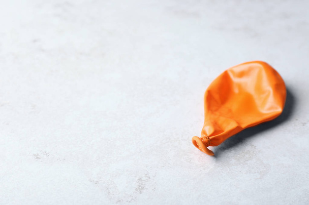 Orange deflated balloon on grey background, space for text - Fotó, kép