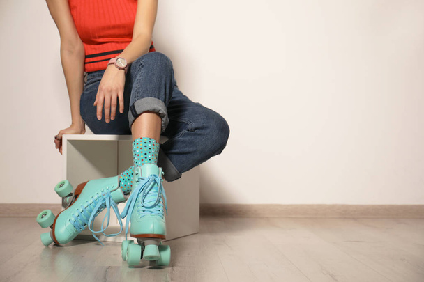 Young woman with retro roller skates against light wall, closeup. Space for text - Foto, immagini