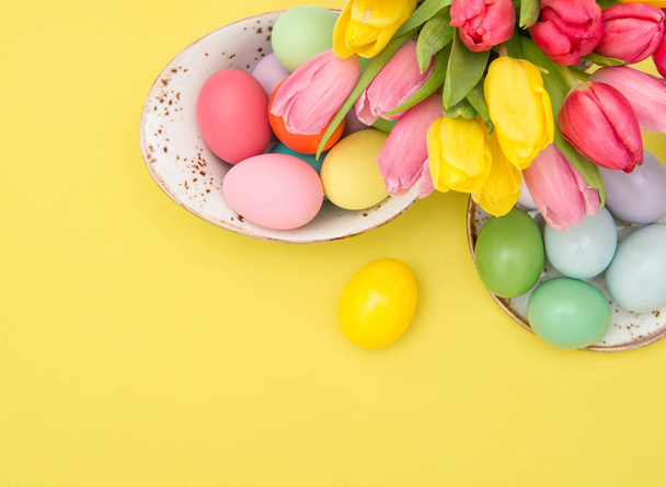 Roze tulp bloemen en Pasen eieren decoratie op gele achtergrond - Foto, afbeelding