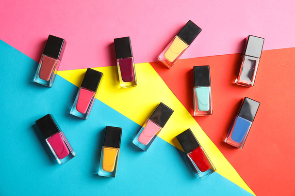 Bottles of nail polish on color background, top view - Φωτογραφία, εικόνα
