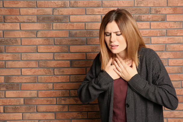 Woman suffering from cough near brick wall. Space for text - Fotó, kép