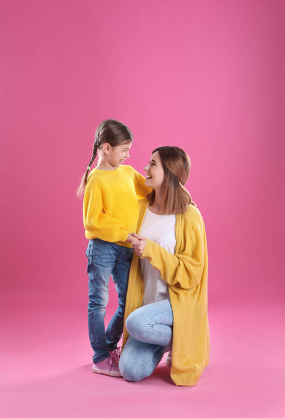 Happy woman and daughter in stylish clothes on color background - Fotó, kép