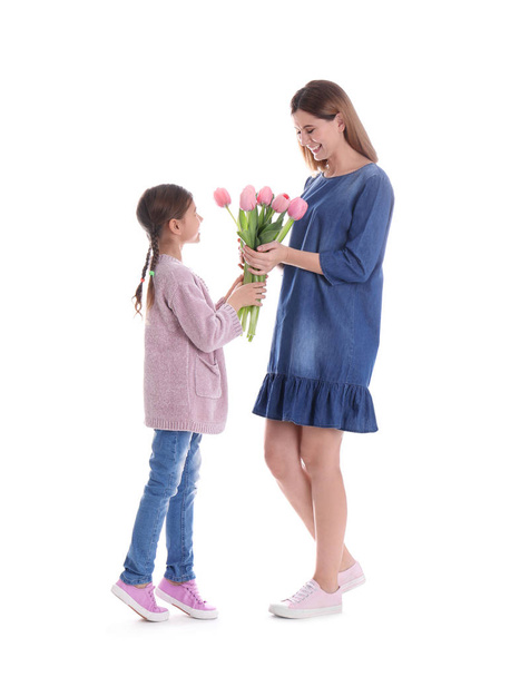 Gelukkig moeder en dochter met bloemen op witte achtergrond. Internationale Vrouwendag - Foto, afbeelding