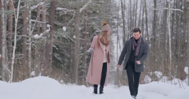 Young married couple in love walking in the winter forest. A man and a woman look at each other laughing and smiling in slow motion. Valentines Day love story. - Footage, Video