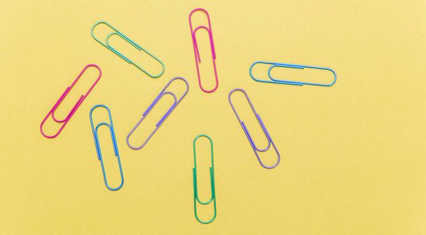 Business, school supplies. Colorful big paper clips on yellow color background - Photo, Image
