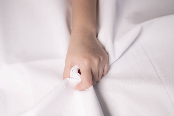 Woman hand squeezing bed sheets color white - Foto, Imagem