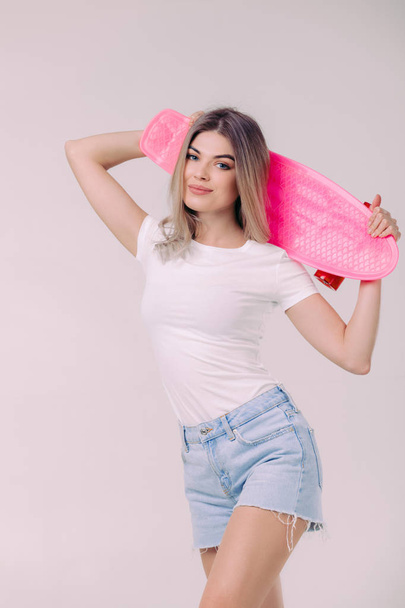 beautiful woman in white t-shirt with pink skateboard - Photo, image