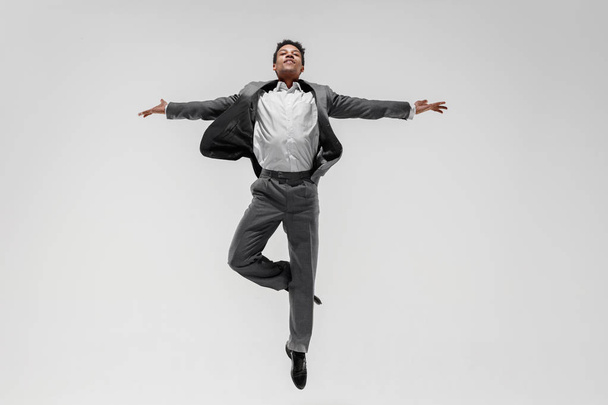 Happy businessman dancing isolated on gray studio background - Foto, immagini