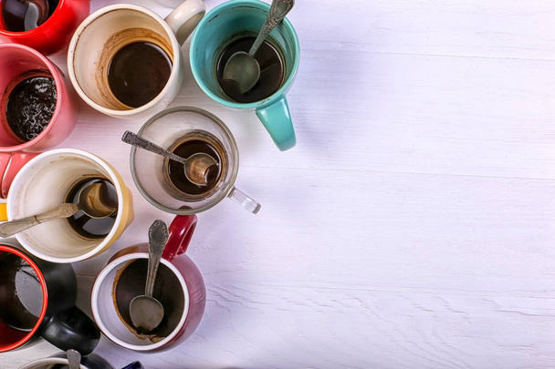 Lege vieze koffie kopjes van verschillende kleuren op tafel. Concept van cafeïne dope, gebrek aan energie en lang wachten. Kopiëren van ruimte. - Foto, afbeelding