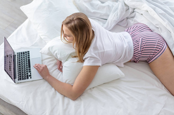 beautiful woman with laptop lying on the bed. - Foto, Bild
