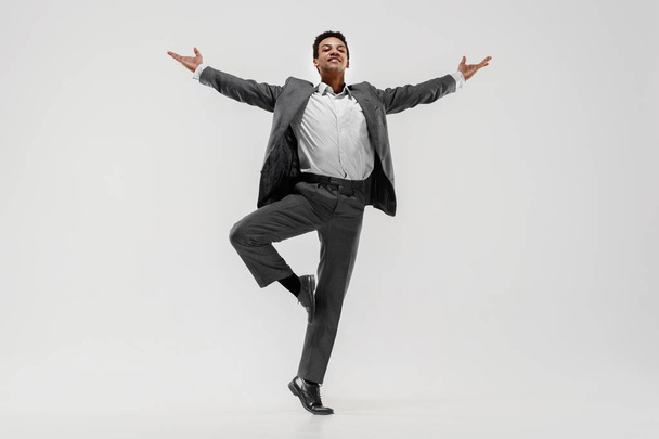 Happy businessman dancing isolated on gray studio background - Photo, image