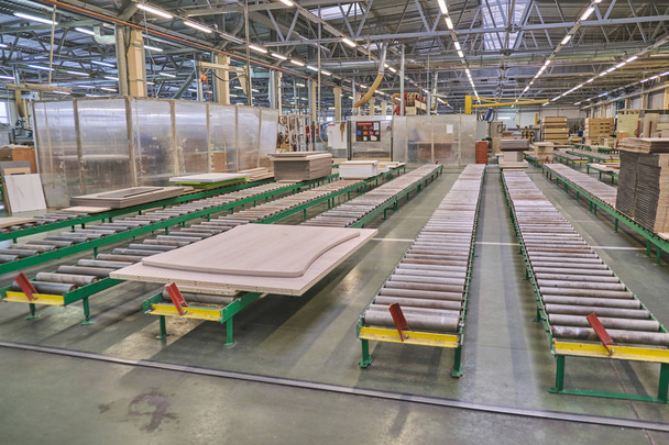 Spanplatten für die Verarbeitung und Produktion von Möbeln in einem holzverarbeitenden Betrieb. Produktionslinie in einer Möbelfabrik. Fräs- und Sägemaschine für die Holzverarbeitung. - Foto, Bild