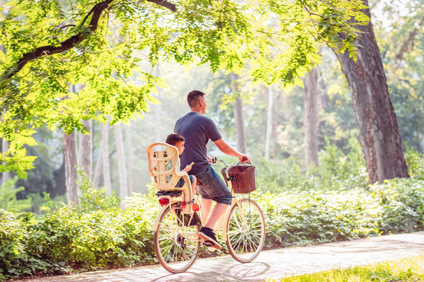 Père actif souriant avec enfant sur des vélos s'amusant dans le parc
. - Photo, image