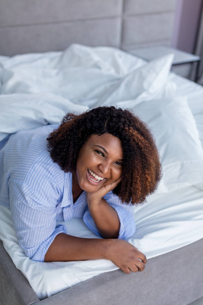 laughing woman posing to the camera while lying under the blanket - Photo, Image