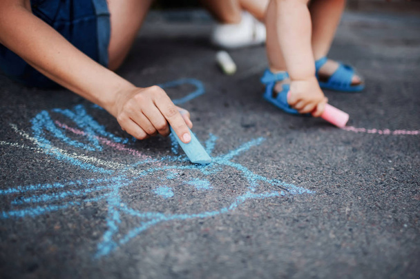 Close up of little girl drawing with chalks on the sidewalk. Kids drawing with chalk - Фото, изображение