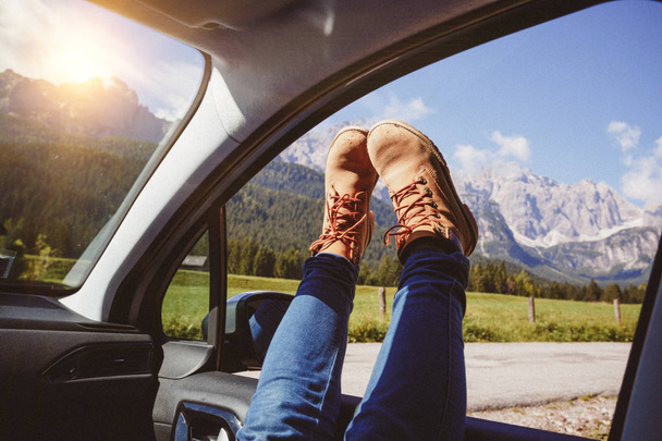 Girl legs in bright boots sticking out of the car. Dolomites, Italy - Zdjęcie, obraz