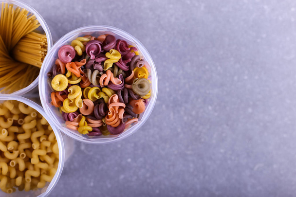 Multicolored pasta with the addition of natural vegetable dye. In jar on a concrete table. Top view, copy Space. - Foto, afbeelding